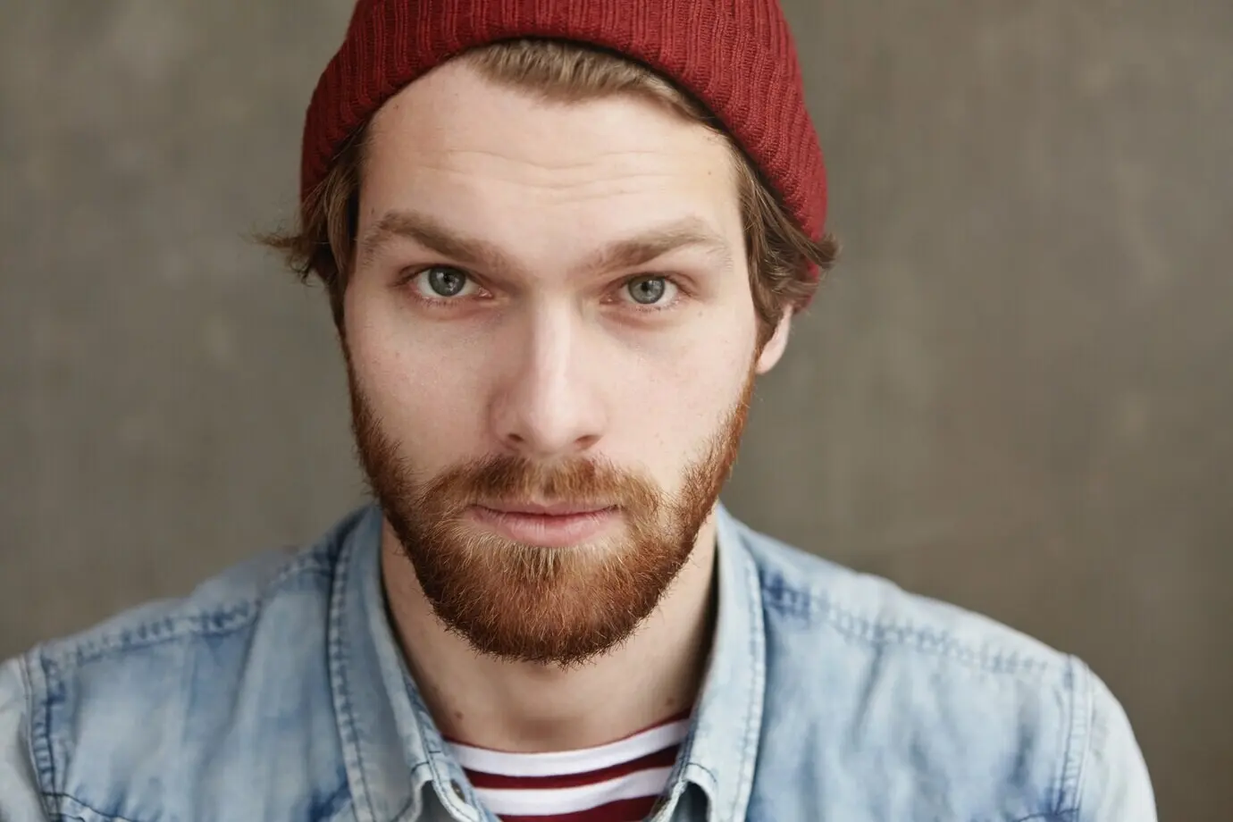 Porträt eines gutaussehenden jungen Hipster-Mannes europäischen Aussehens, der in Innenräumen posiert.